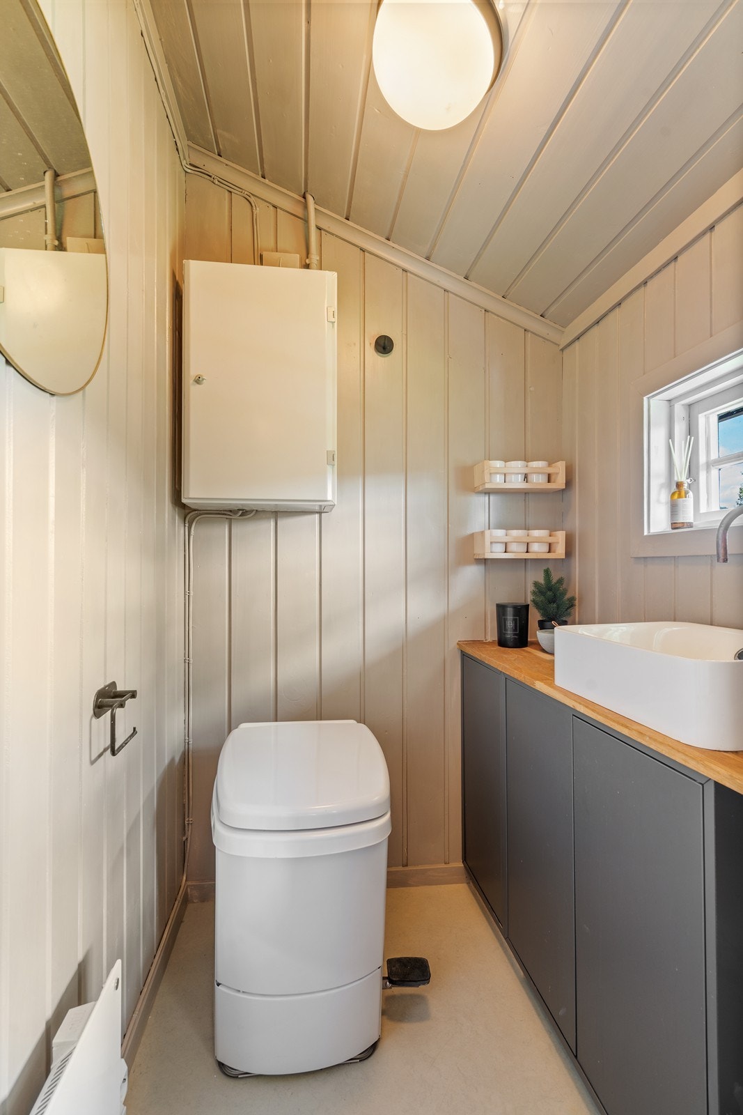 Toalettrom med forbrenningstoalett og servant med innredning hvor vannet pumpes med fotpumpe for vann. Galleribilde