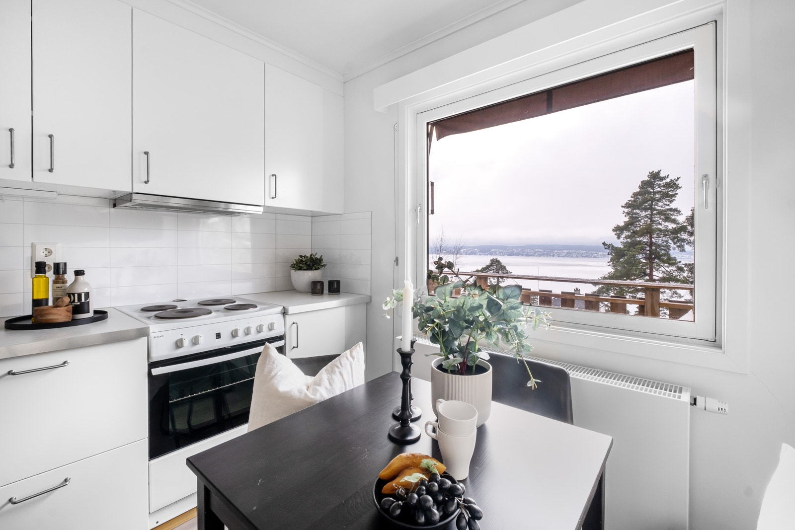 Kjøkken med hvitevarer og plass til frokostbord Galleribilde