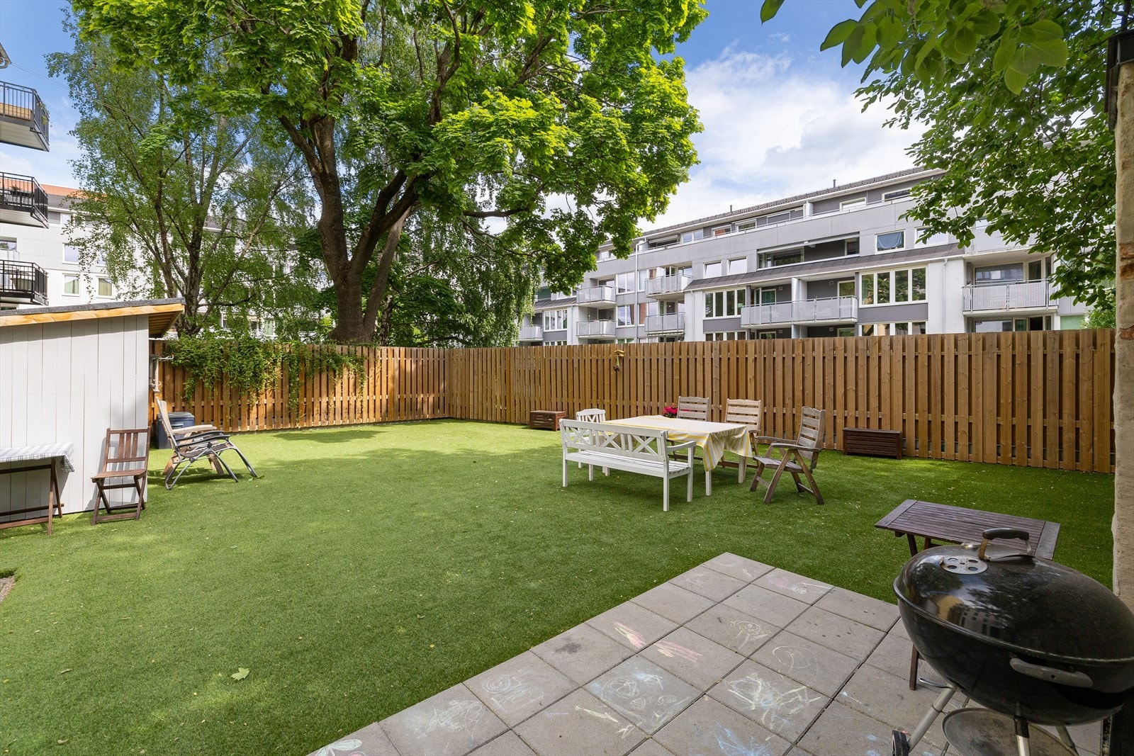 Pent opparbeidet bakgård med sittegrupper, grill og sykkelparkering. Galleribilde