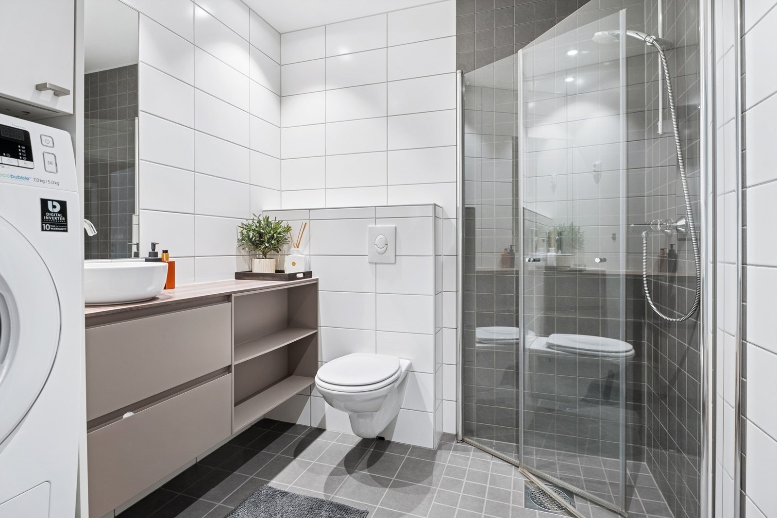 Baderommet har flislagte vegger og gulv med varmekabler | Vegghengt toalett | Romslig dusjhjørne Galleribilde