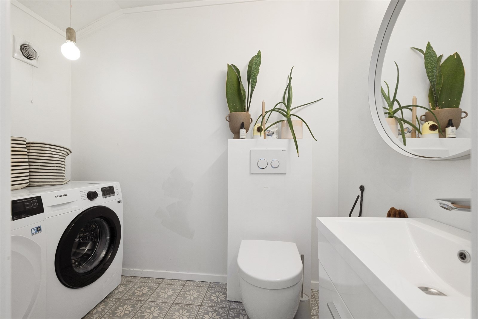 Vaskerommet i første etasje er praktisk innredet med servant i underskap med skuff og ettgreps blandebatteri, veggmontert toalett samt opplegg for både vaskemaskin og tørketrommel Galleribilde