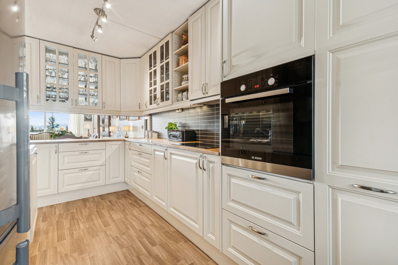 Kjøkkeninnredningen er lys og tidløs, med profilerte fronter og integrerte hvitevarer som stekeovn, platetopp og oppvaskmaskin. Galleribilde