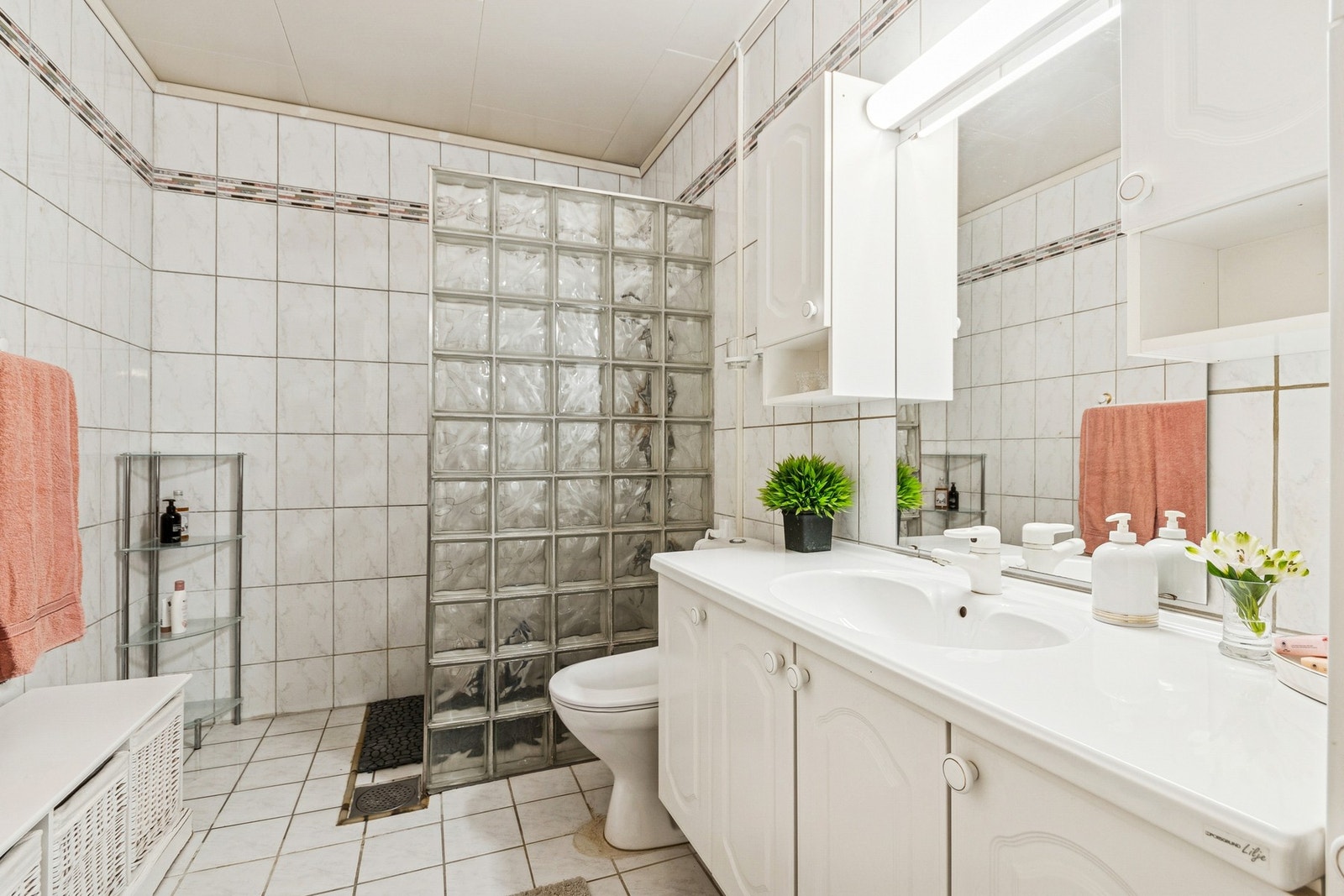 Flislagt bad med elektriske varmekabler i gulv. Innredning med servant, over- og underskap, toalett og dusjnisje. Galleribilde