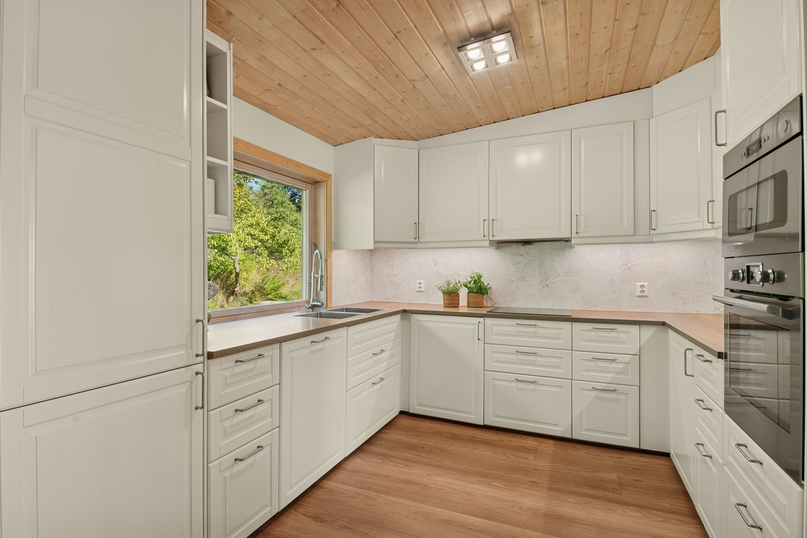 Moderne kjøkken med hvite profilerte fronter og integrerte hvitevarer. Galleribilde