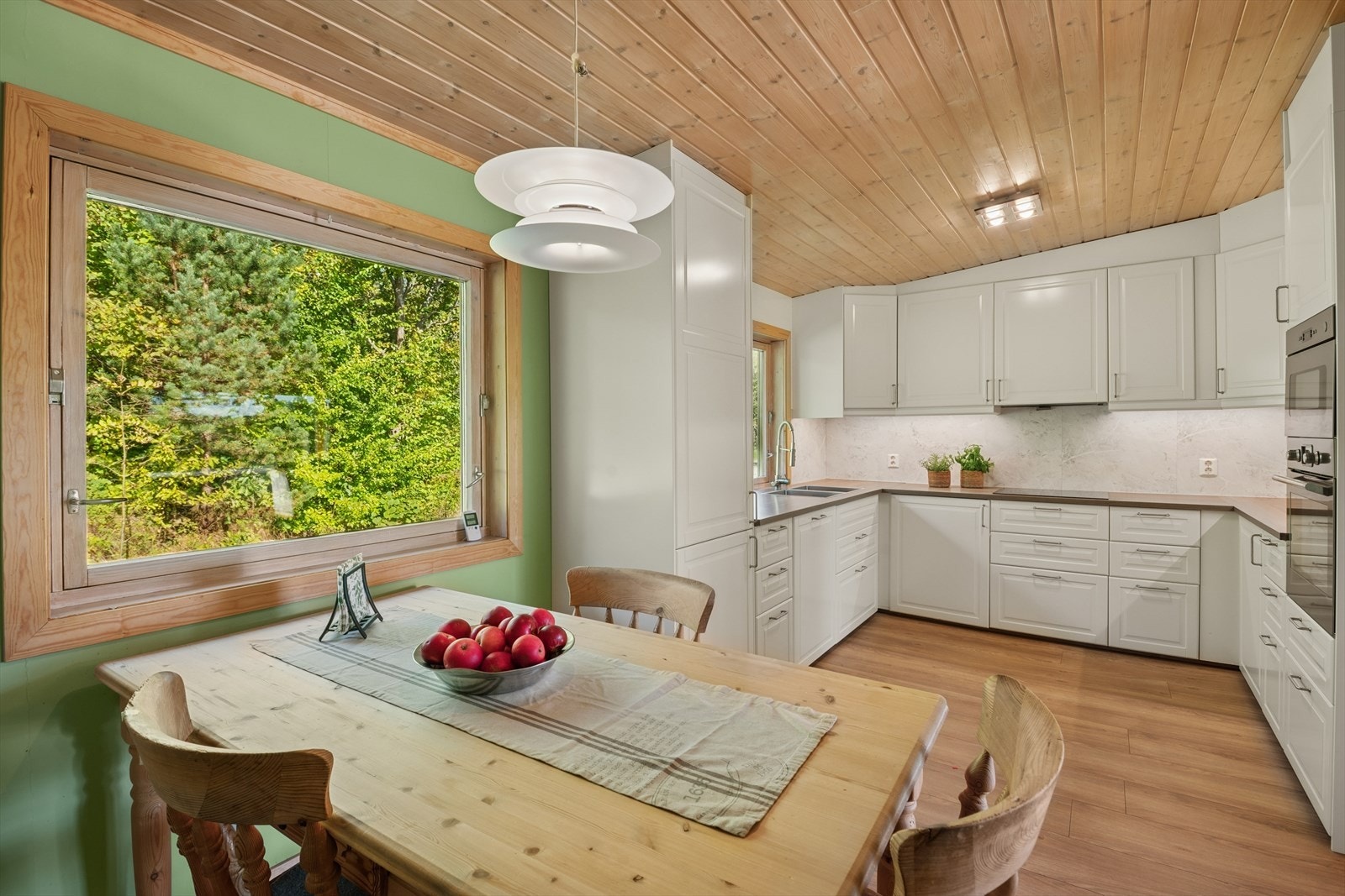 Kjøkken med god skapplass og spiseplass ved vindu med utsyn mot grønne omgivelser Galleribilde