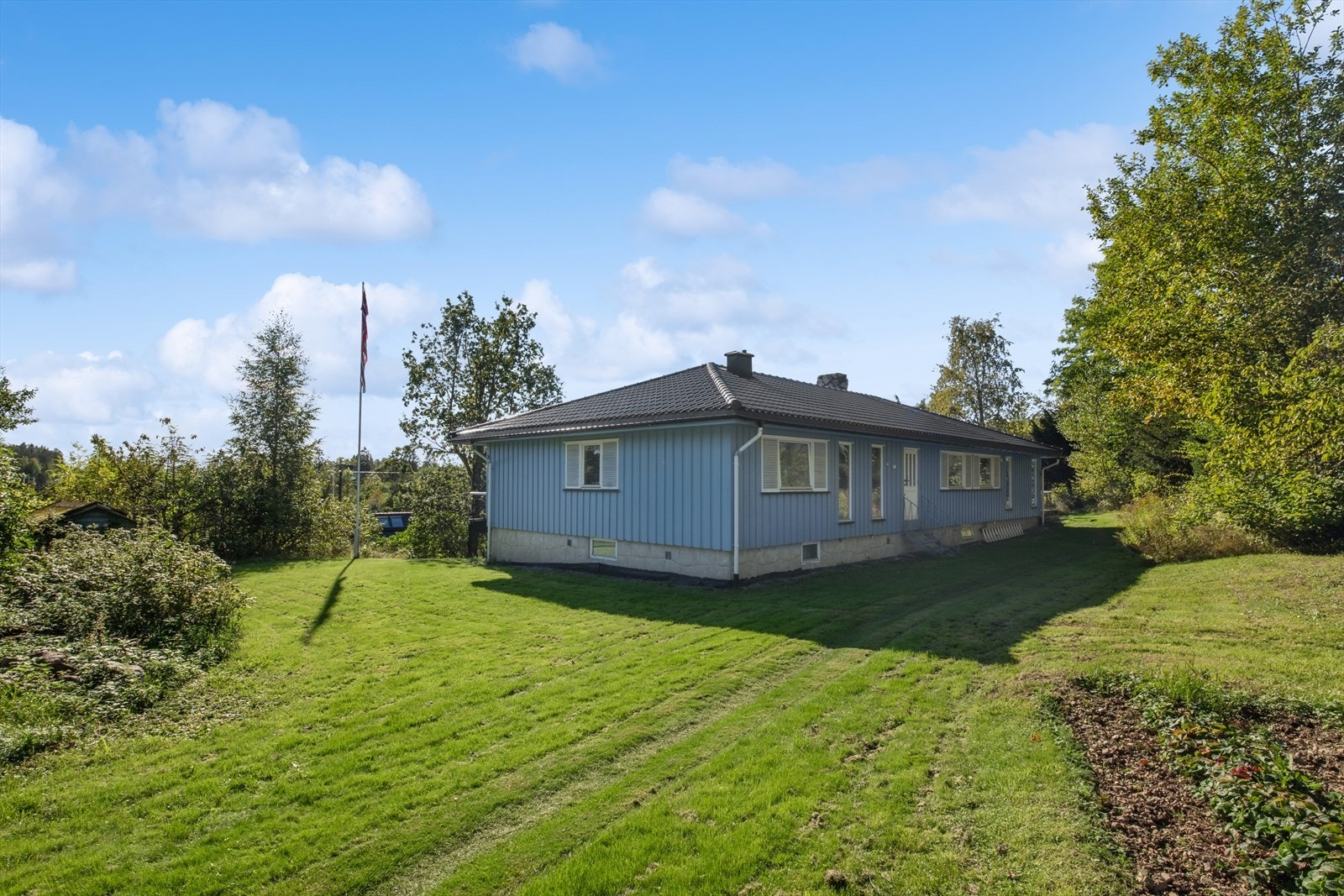 Boligen ligger på en romslig tomt med stor hage og gode solforhold Galleribilde