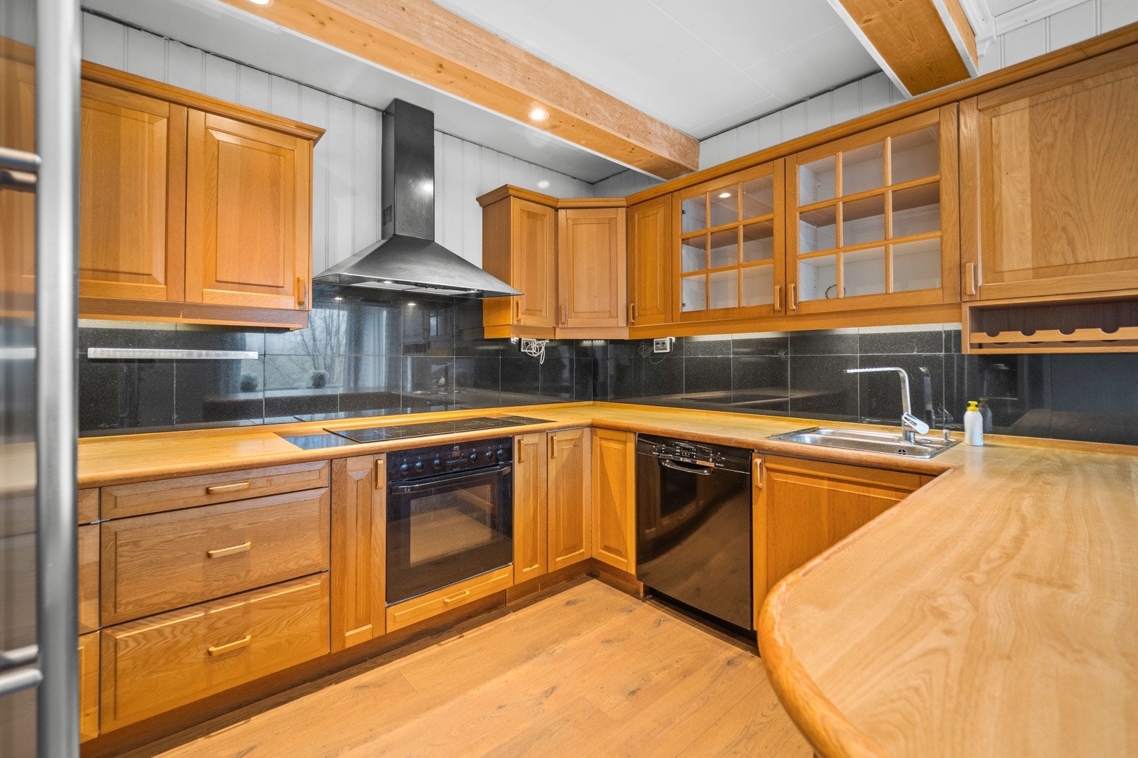 Kjøkkeninnredning med slette fronter og integrerte hvitevarer, samt frittstående kjøleskap Galleribilde