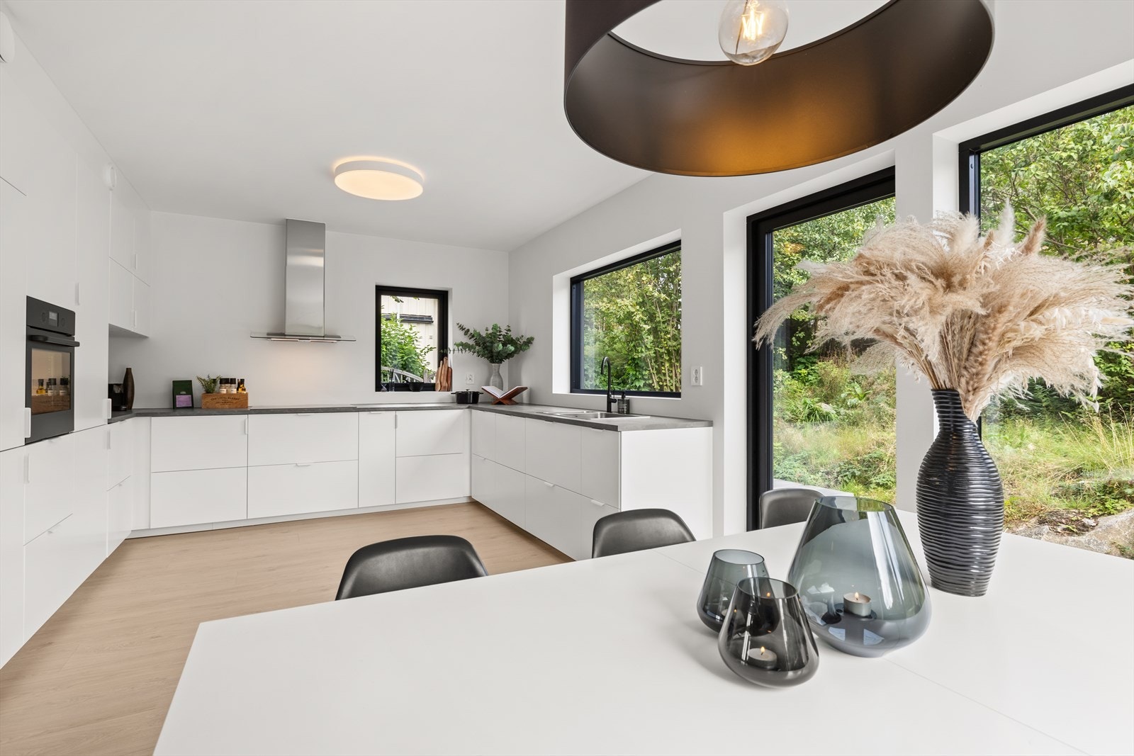 Kjøkkenet er stilrent og funksjonelt med IKEA-innredning fra 2024 i hvite, glatte fronter kombinert med en praktisk laminat benkeplate og nedfelt oppvaskkum. Galleribilde