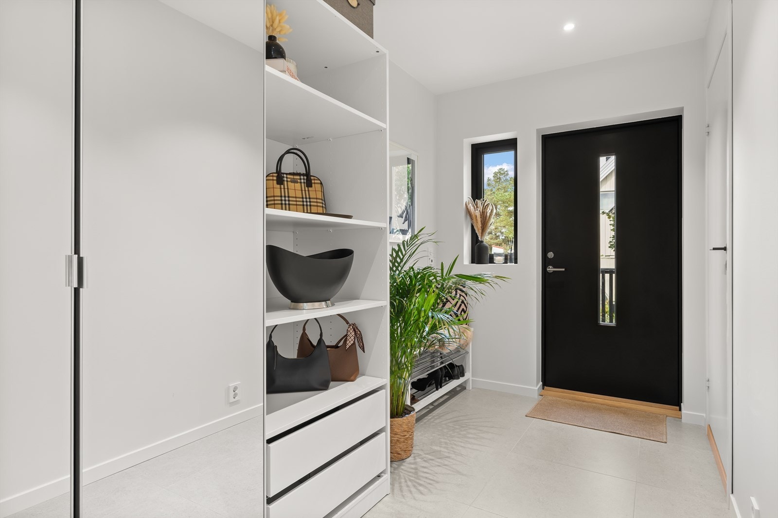 Boligen ønsker dere velkommen med en romslig og stilren entré. Her er det lagt store, moderne fliser med elektrisk gulvvarme som gir både komfort og en lun velkomst, særlig på kalde dager. Galleribilde