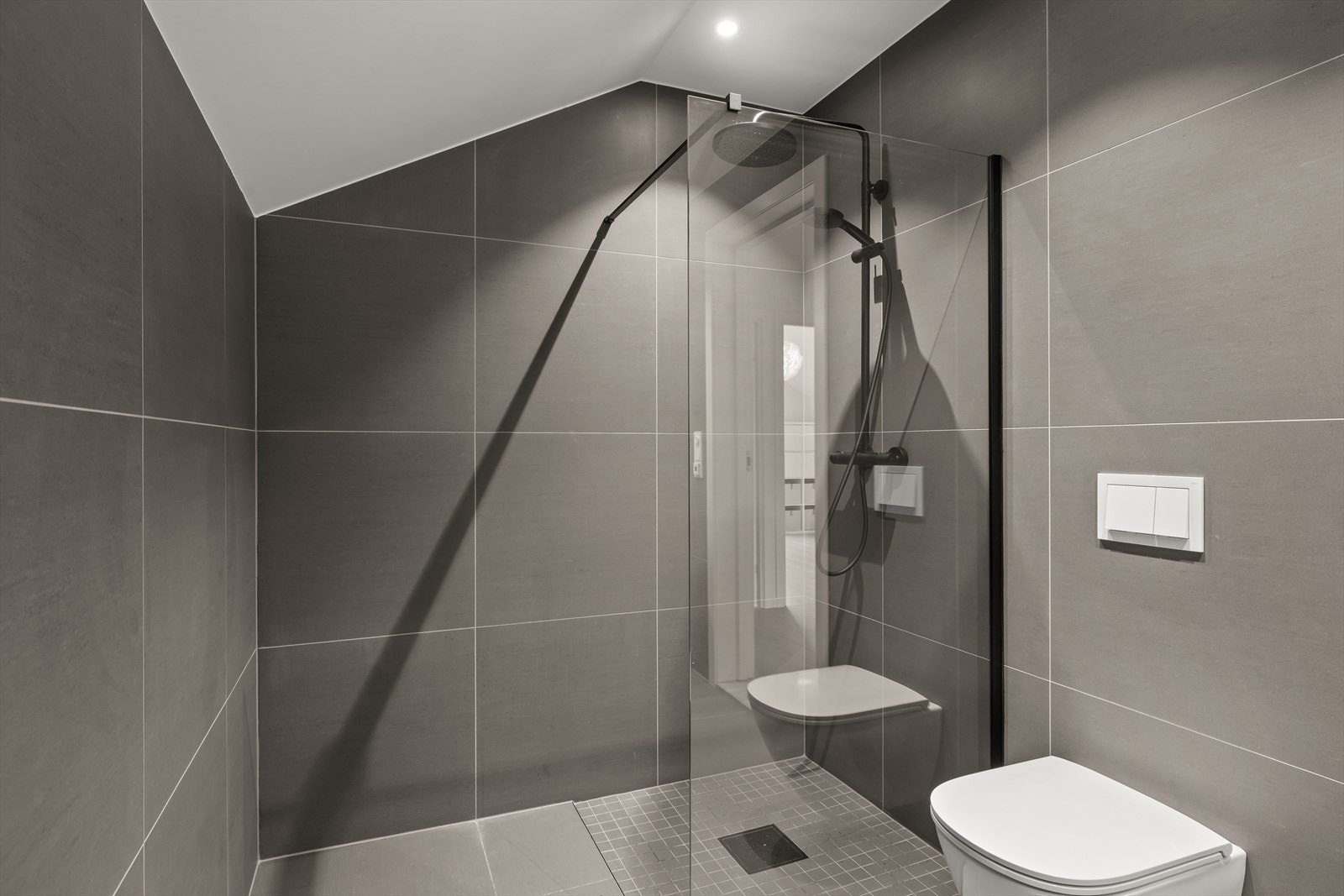 Her finner du en nedsenket dusjsone med glassvegg, vegghengt klosett, heldekkende servant med innredning og speilskap som gir både funksjonalitet og rikelig oppbevaring. Galleribilde