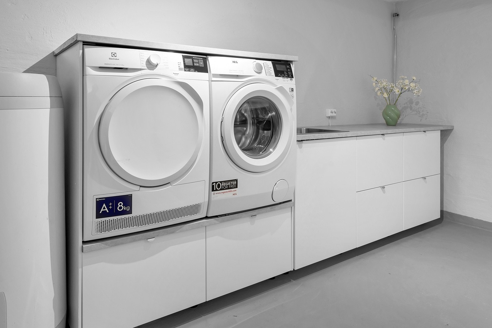 Smart innredet vaskerom med vask, vaskemaskin, tørketrommel, benk og oppbevaring. Galleribilde