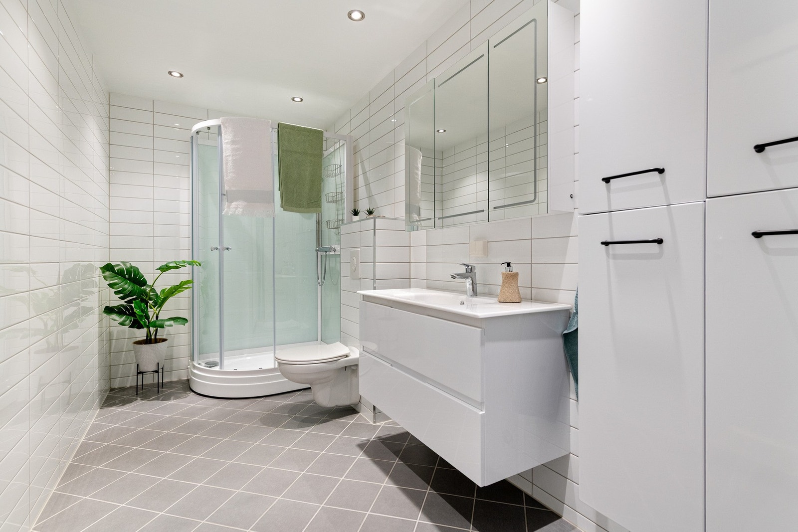 Pent flislagt bad. Rommet inneholder: Servantskap, oppbevaring, toalett og stort dusjkabinett. Galleribilde