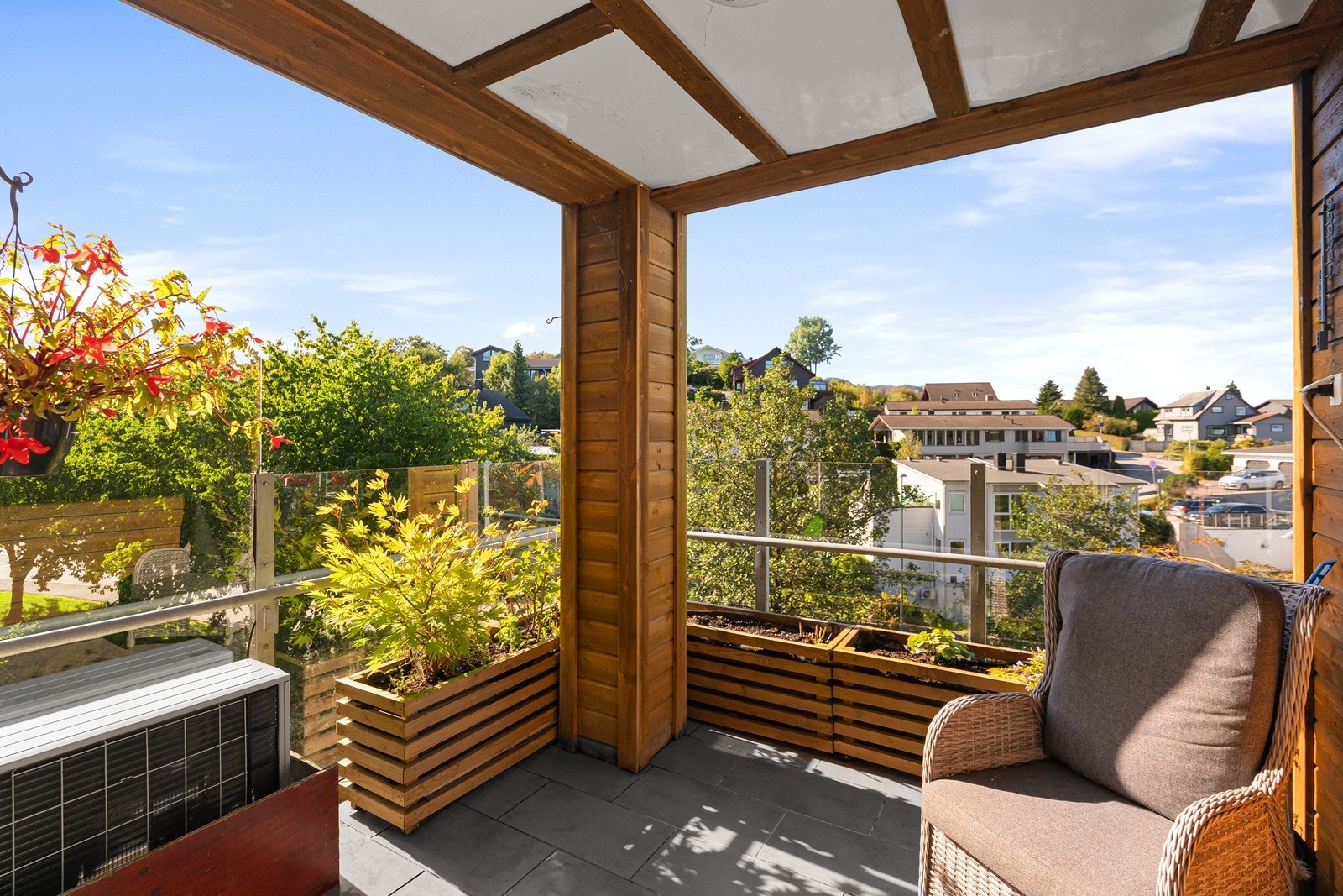 Nydelig balkong med stilrent glassgelender og overbygg med hvite plater i tak. Uteplassen fungerer som en grønn forlengelse av leiligheten. Galleribilde