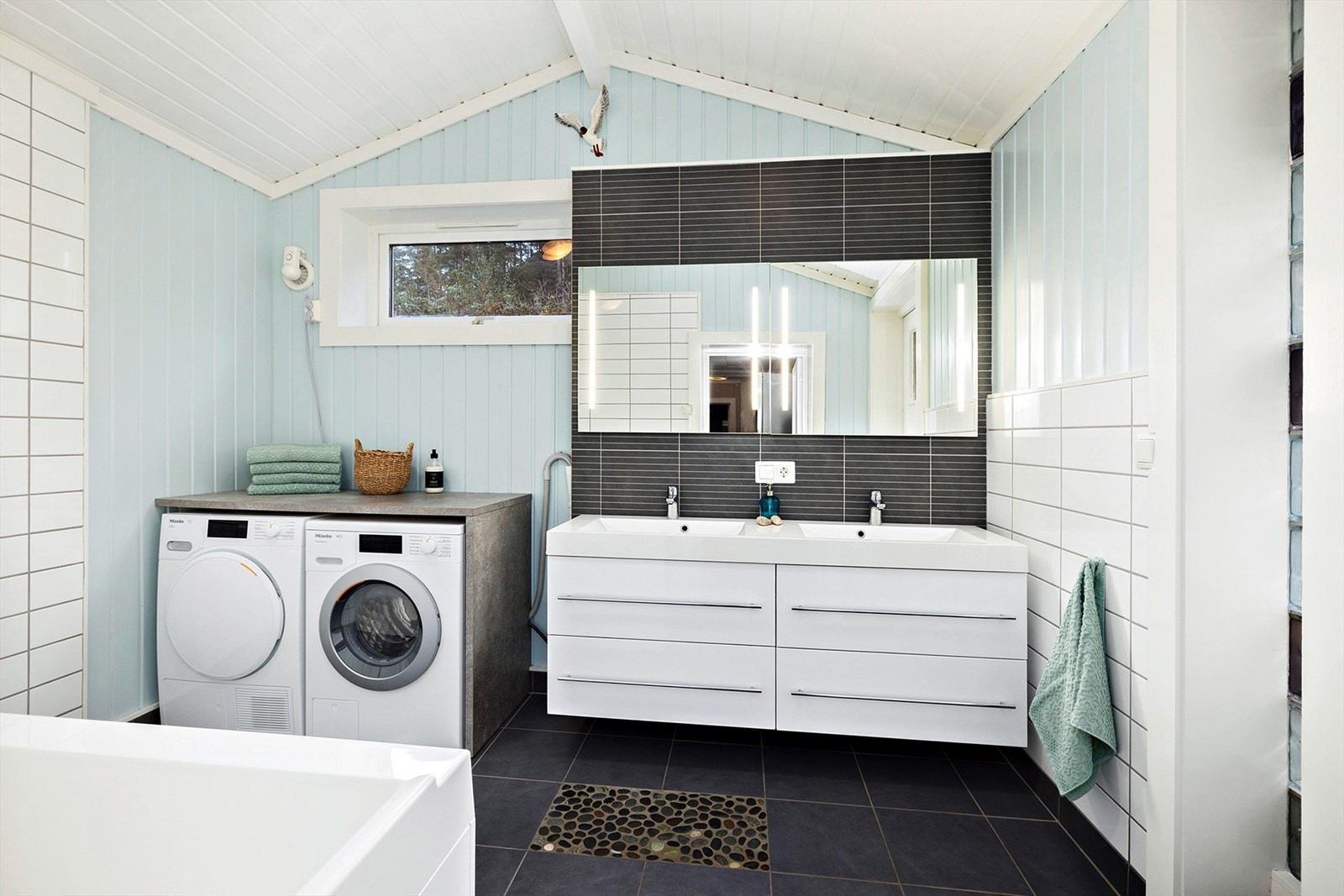 Vaskerom/bad på innsiden av kjøkkenet. Her er det badekar, baderomsmøbel dobbel servant, og opplegg for vaskemaskin. Galleribilde