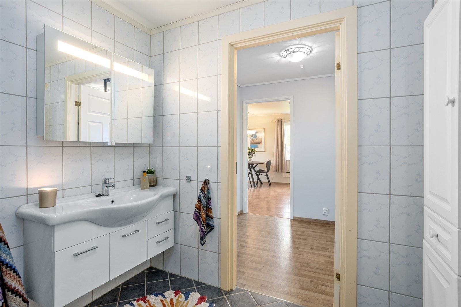 Baderomsinnredningen består av nedfelt servant i skapseksjon, toalett, dusjkabinett, utslagsvask og opplegg for vaskemaskin. Galleribilde