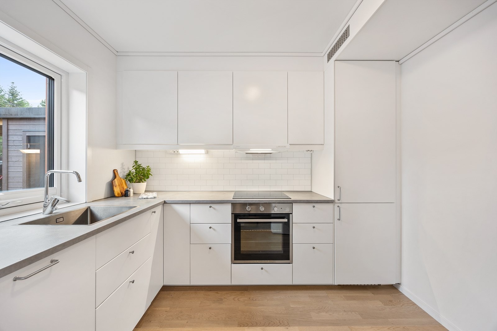 Stilrent kjøkken med integrerte hvitevarer og god belysning under overskapene. Galleribilde