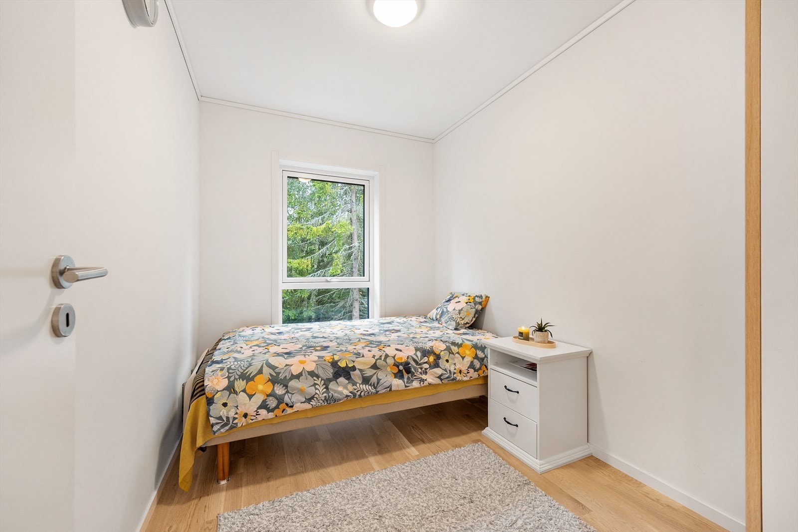 Lyst og trivelig soverom med parkett på gulvet og malte veggflater. Galleribilde