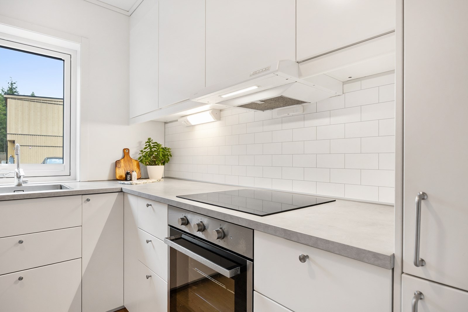 Stilrent kjøkken med integrerte hvitevarer og god arbeidsbelysning under overskapene. Galleribilde