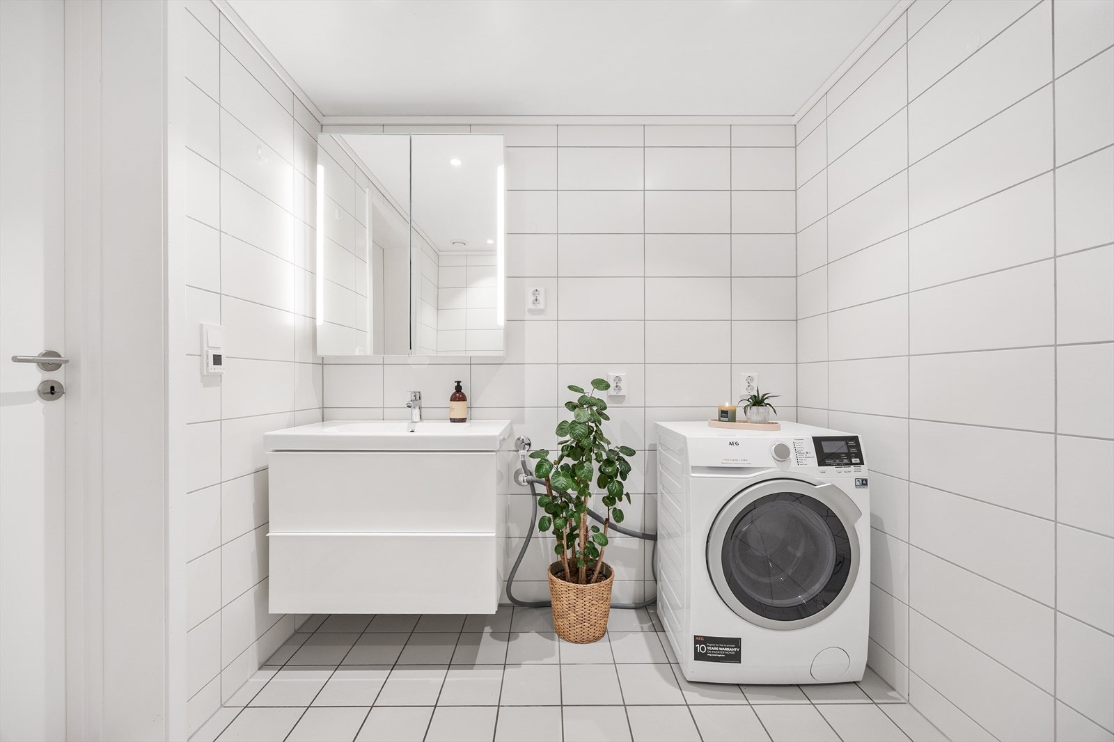 Baderomsinnredning med servantseksjon med skuffer og speilskap med integrert lys. Galleribilde