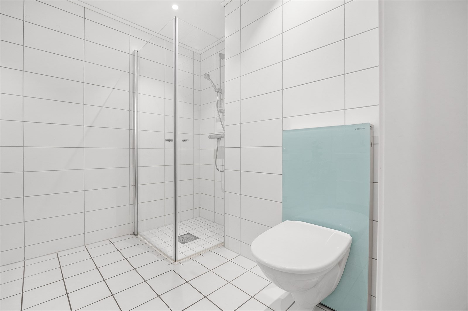 Nedsenket dusjnisje med elegante glassdører og praktisk plastsluk med klemring. Galleribilde