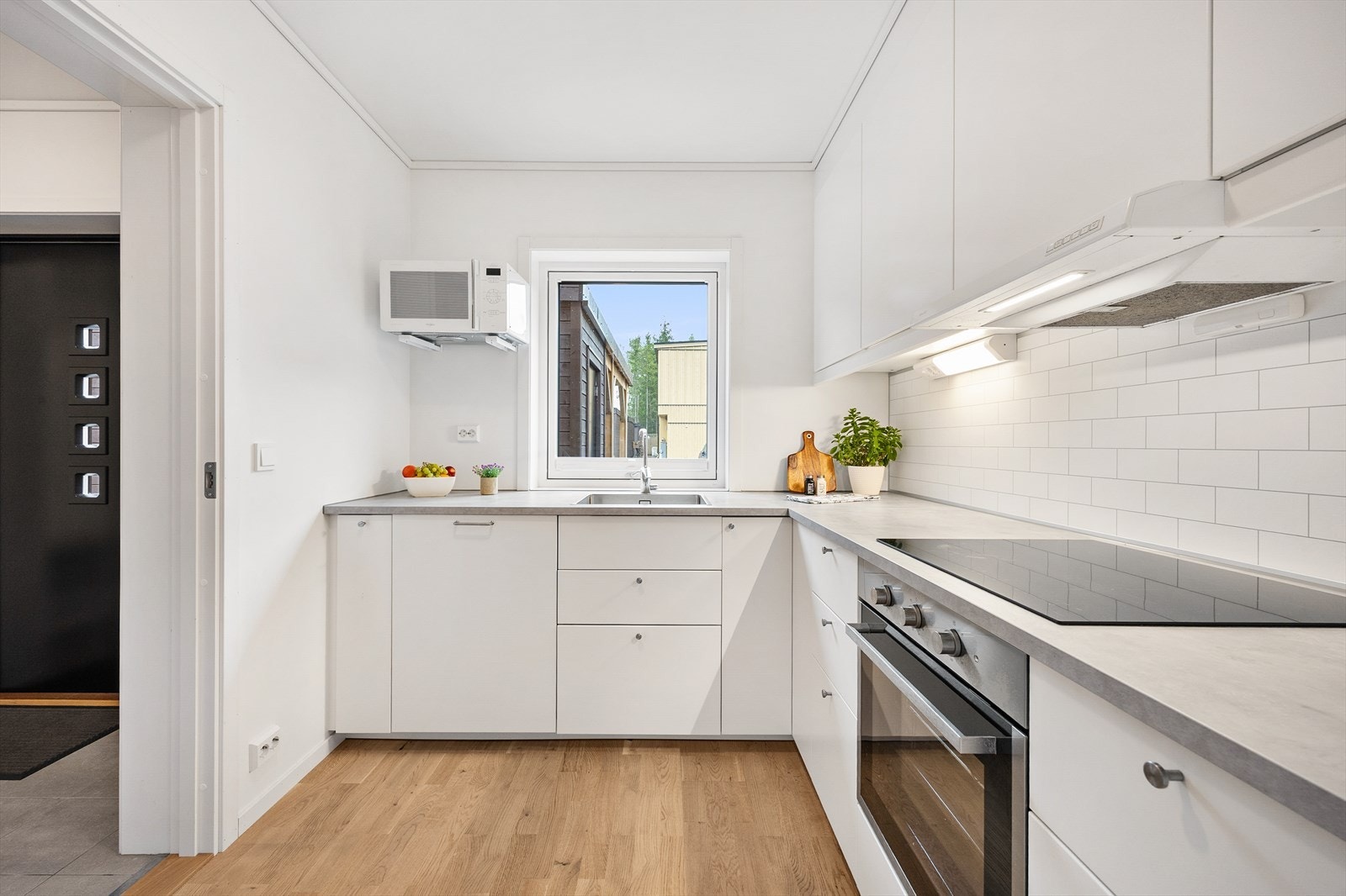 Arealeffektiv kjøkkenløsning med glatte, hvite fronter og slitesterk laminatbenkeplate. Galleribilde