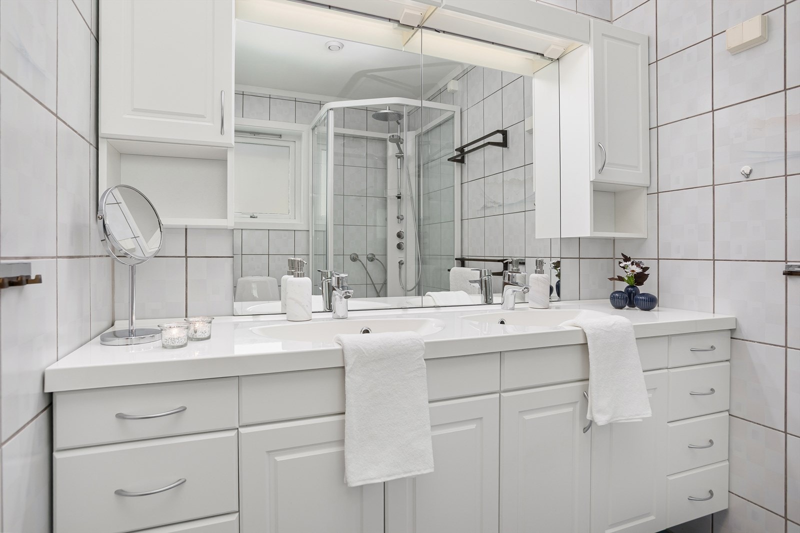 Badet er utstyrt med dobbel heldekkende servant med underskap, speil, veggskap, dusjkabinett og toalett Galleribilde