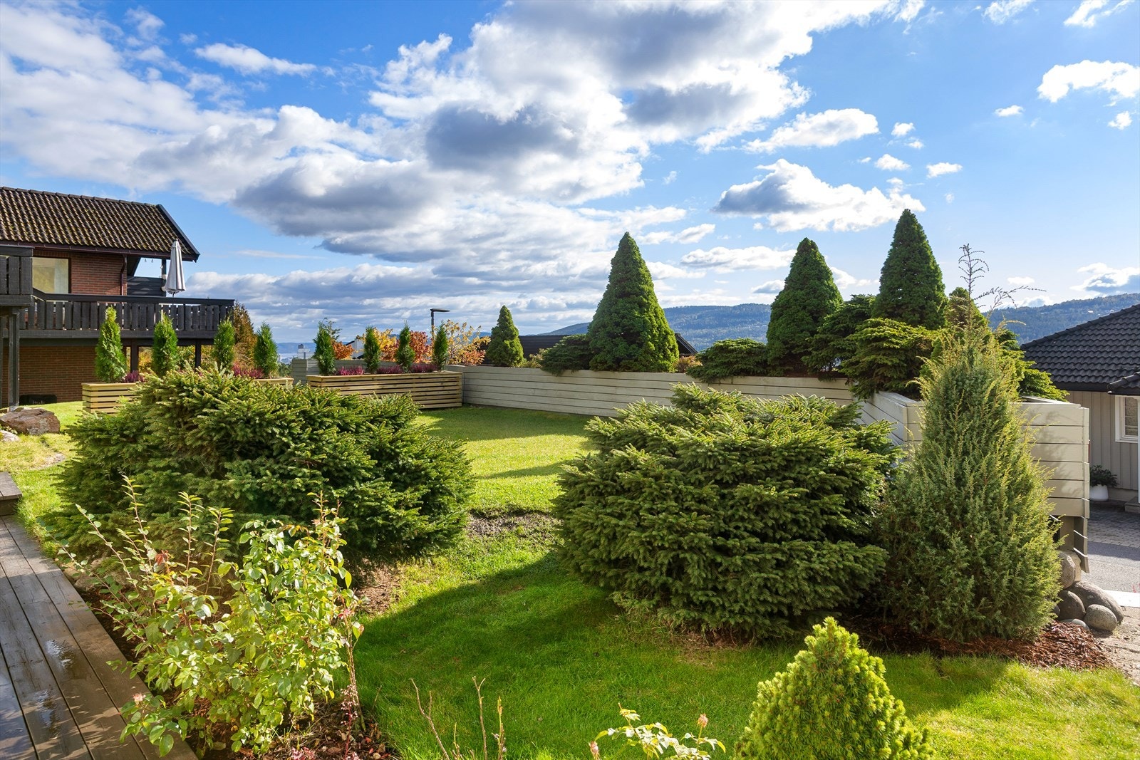 Frodig plen, prydbusker, hekk og vintergrønne trær som gir både privatliv og en lun atmosfære året rundt Galleribilde
