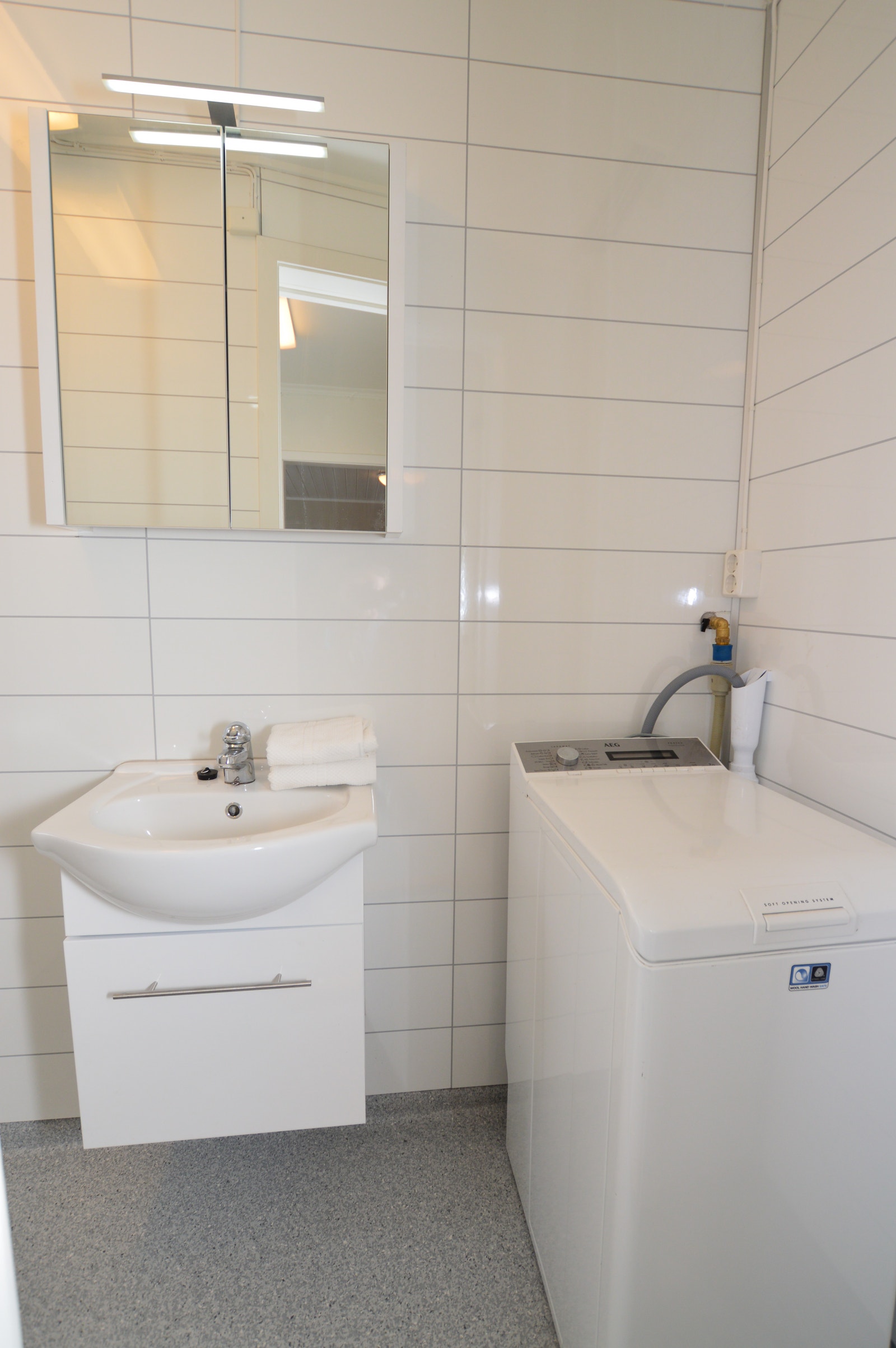 Bad med servant med underskap, speilskap og vaskemaskin. Galleribilde