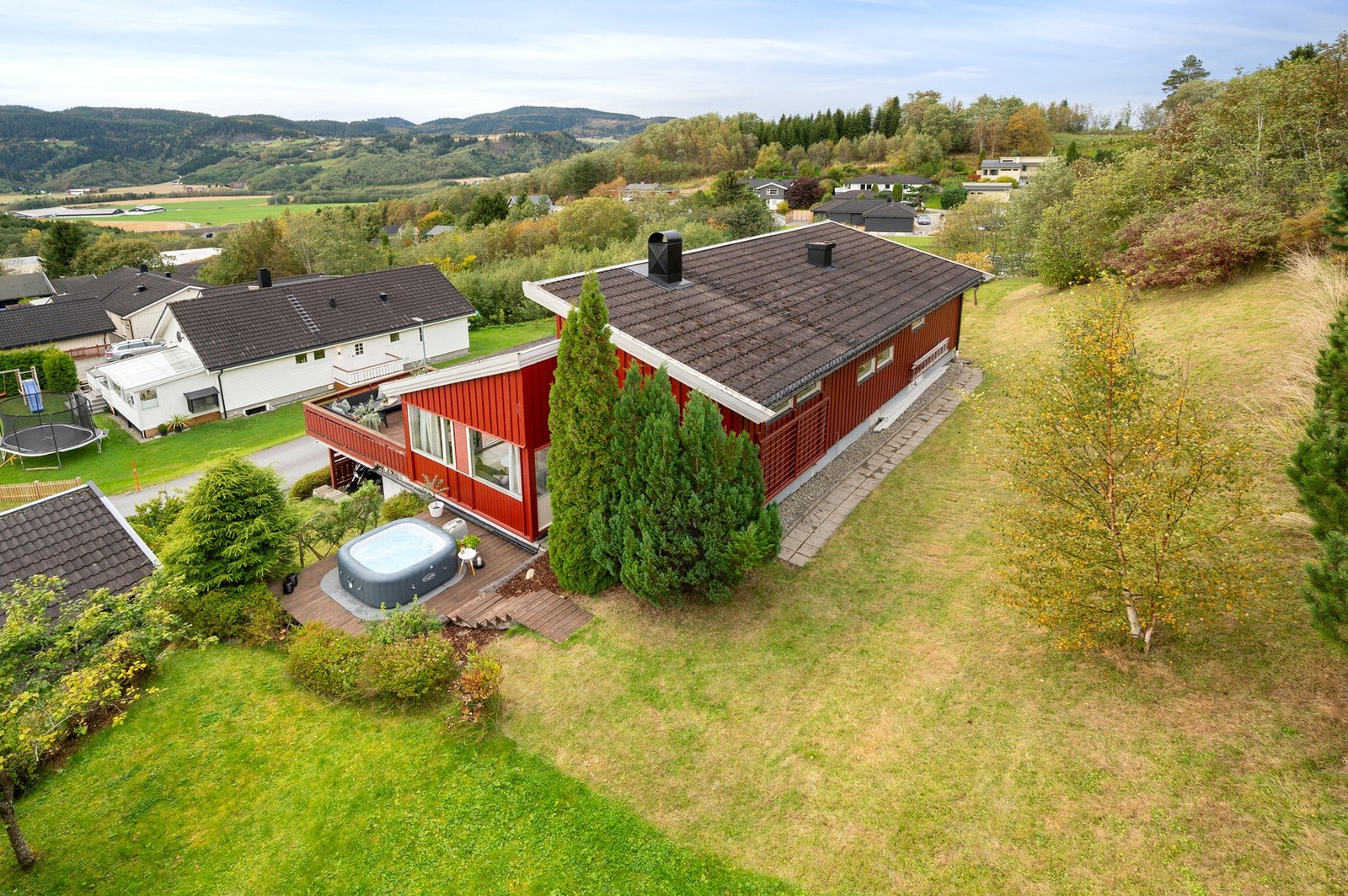 Boligen har en romslig plen med flere buskevekster. Galleribilde