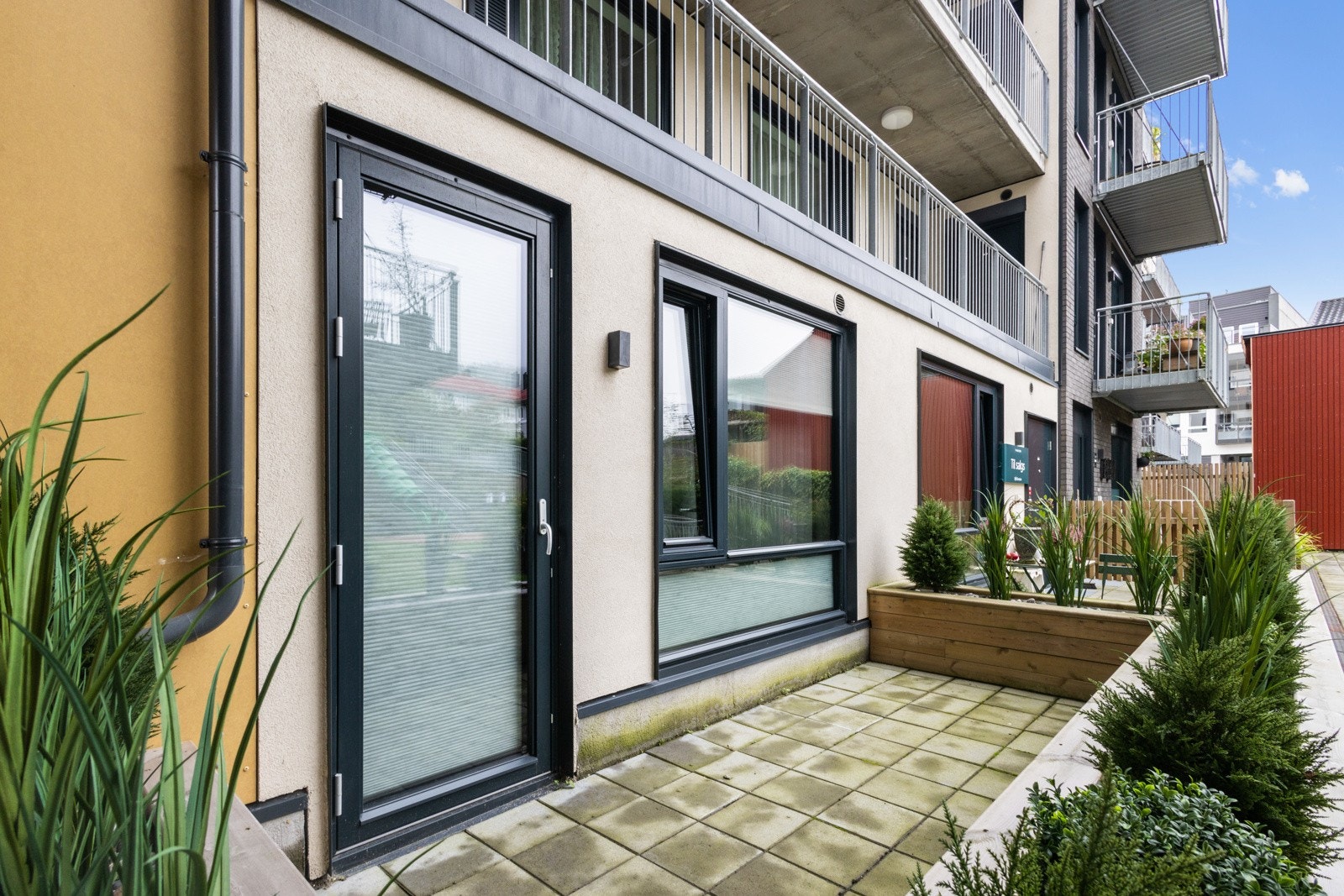 Nordøstvendt terrasse med adkomst fra soverom som vender inn mot frodig atrium med lekeplass. Galleribilde