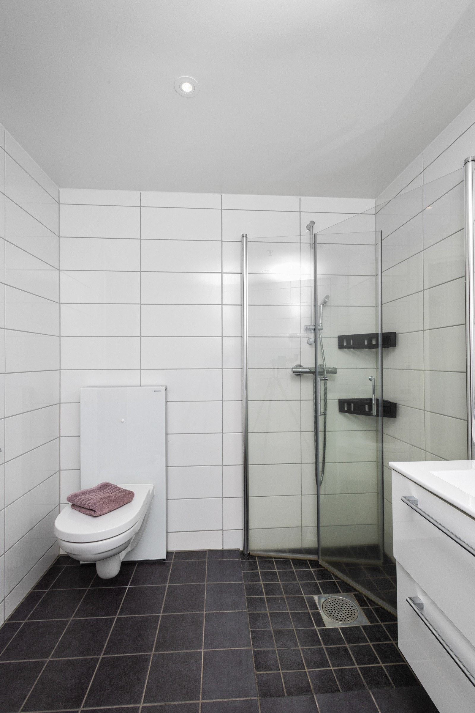 Baderommet inneholder: servant, speil m/belysning, dusjhjørne, veggmontert wc og opplegg for vaskemaskin/trommel. Galleribilde