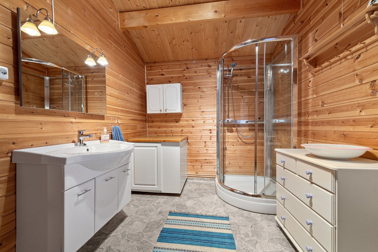 Badet har innredning med servant, speil, dusjkabinett og toalett. Galleribilde