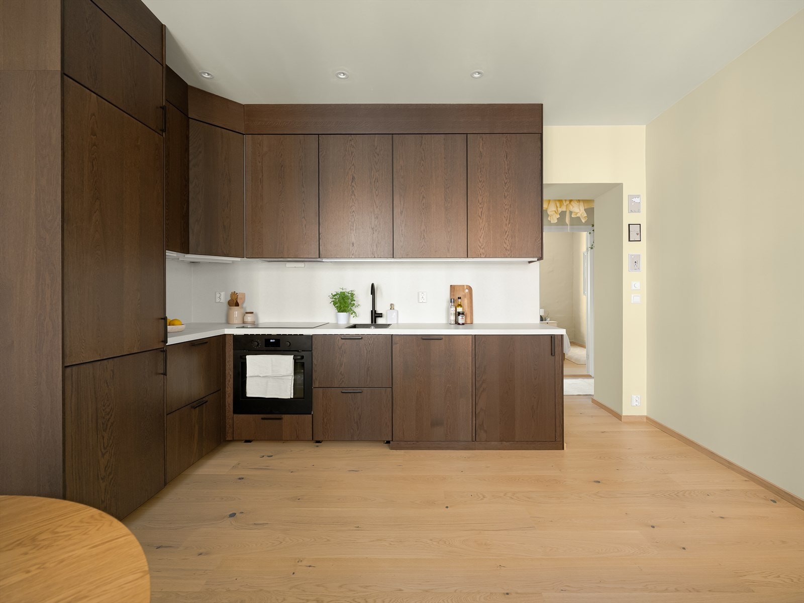 Innredningen har over- og underskap med slette fronter, laminert benkeplate med nedfelt vask og platetopp. Bak kjøkkendør er det en frittstående vaskemaskin. Galleribilde