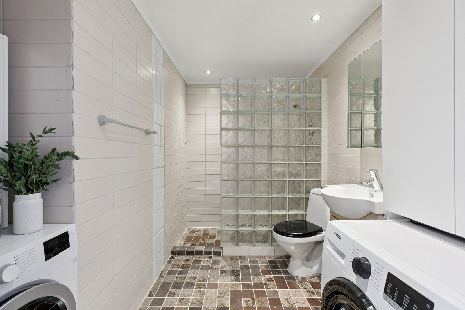 Badet er innredet med både vaskemaskin og tørketrommel, og har god skapplass over vaskesonen. Moderne overflater og praktisk løsning gir en funksjonell og ryddig hverdag. Galleribilde