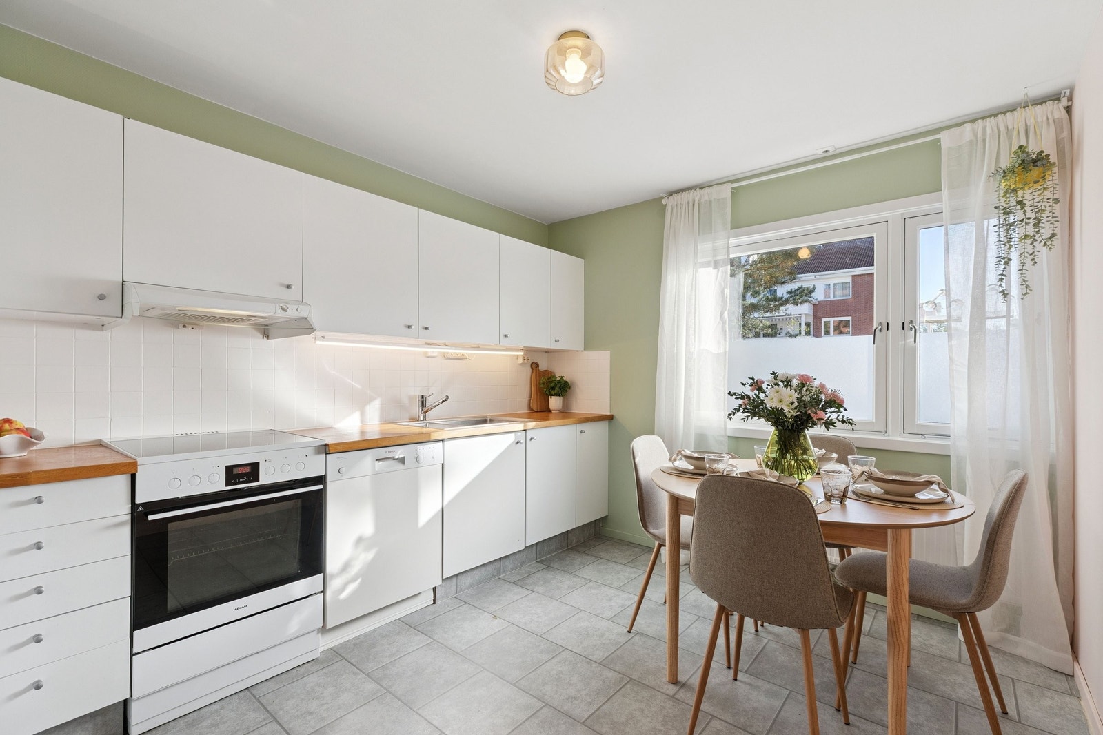 Separat kjøkken med lyse overflater og spiseplass til flere personer. Kjøkkenet har god skapplass og praktisk utforming – Perfekt for både hverdag og hyggelige middager. Galleribilde