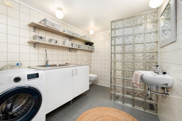 Felles bad/vaskerom i bakgård. Servantskap, skyllekum, servant, dusjnisje, veggmontert wc. Vaskemaskin og tørketrommel. Galleribilde