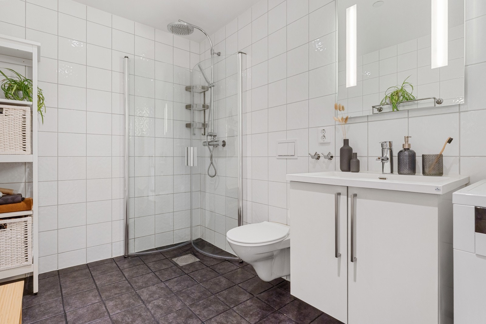 - Badet er innredet med fliser på både gulv og vegger, og inneholder vegghengt toalett, helstøpt servant med skap, dusjdører i glass og opplegg for vaskemaskin - Galleribilde