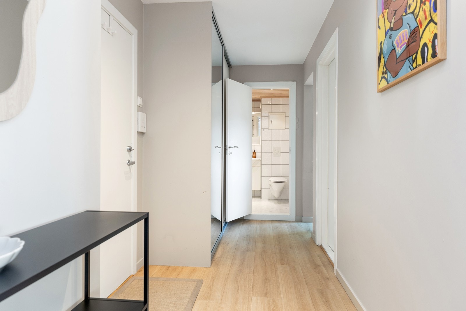 En praktisk skyvedørsgarderobe med speilfronter gir rikelig med oppbevaringsplass samtidig som den bidrar til å åpne opp rommet og reflektere lyset. En funksjonell og stilren entré som binder boligen sammen på en elegant måte. Galleribilde