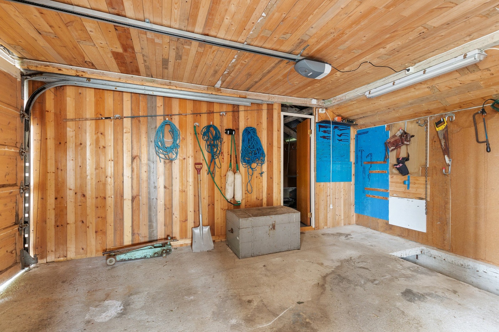 Garasjen har støpt betongdekke og elektrisk port på ene delen. Galleribilde