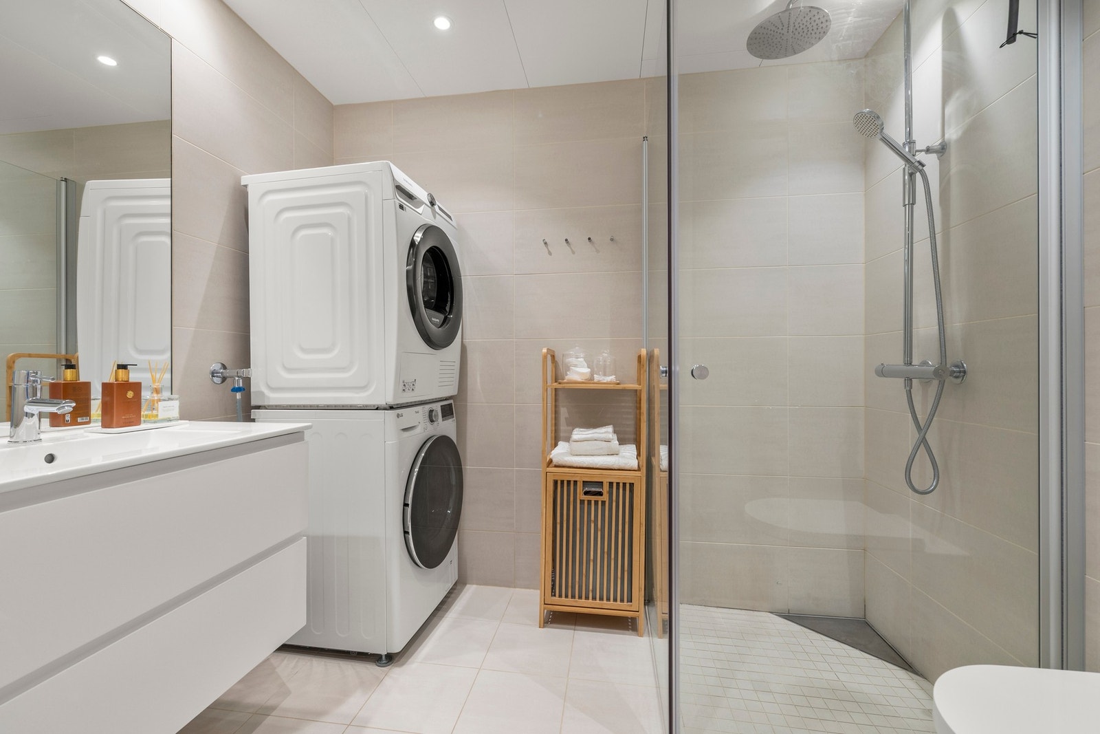 Rett innenfor entréen ligger det første av leilighetens to bad. Her er det delikate flislagte overflater og himlingsplater med downlights som gir god belysning. Galleribilde