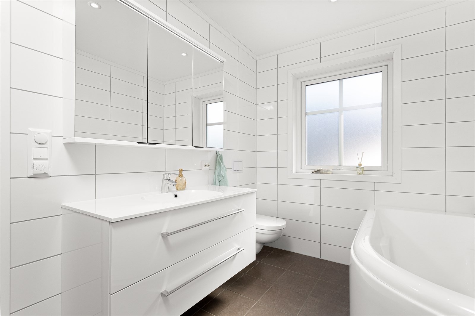 Romslig og moderne baderomsinnredning med mye oppbevaringsplass for baderomsartikler. Galleribilde