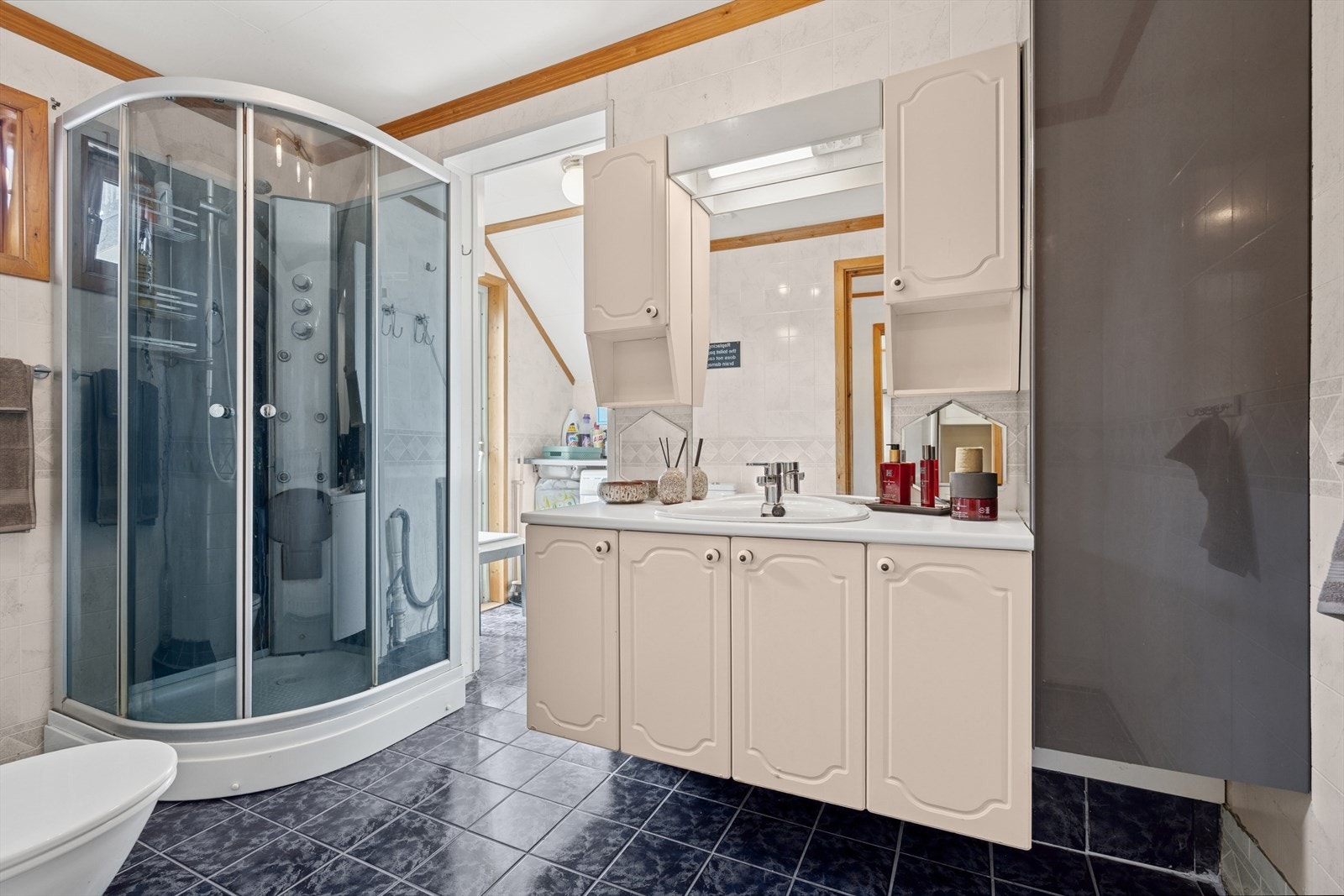 Baderommet har en innredning med nedfelt servant, speil med overliggende lys, toalett og dusjkabinett. Galleribilde