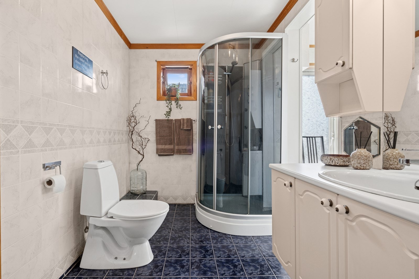 Flislagt baderom som ligger vegg i vegg med eget vaskerom. Galleribilde