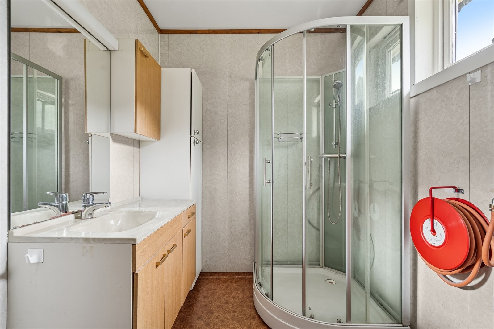 Badet er innredet med nedfelt servant med underskap og speil, gulvstående toalett og dusjkabinett. Galleribilde