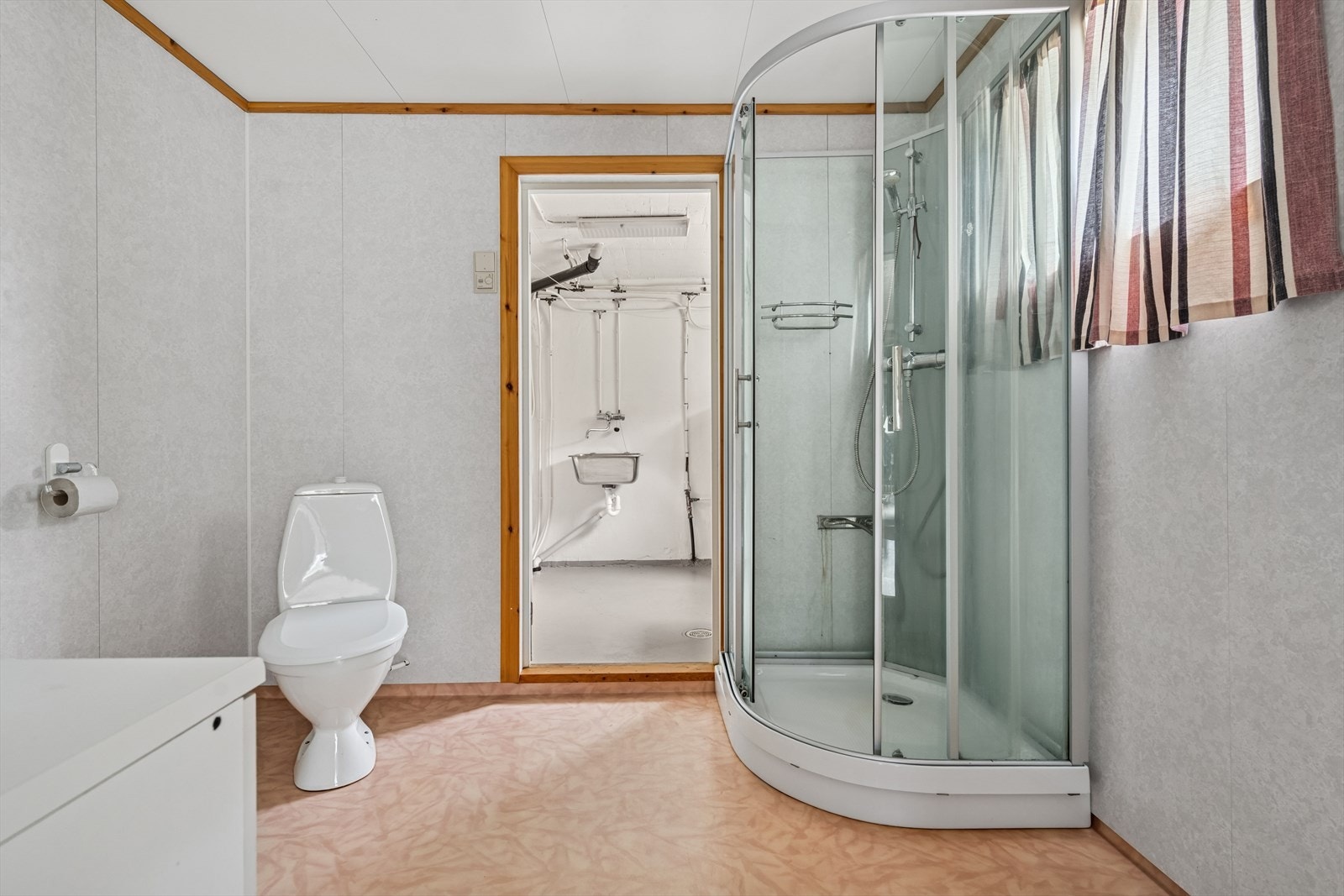 Badet i kjelleren er innredet med gulvstående toalett, dusjkabinett og servant med underskap. Boligen har ett bad og vaskerom i hver etasje. Galleribilde