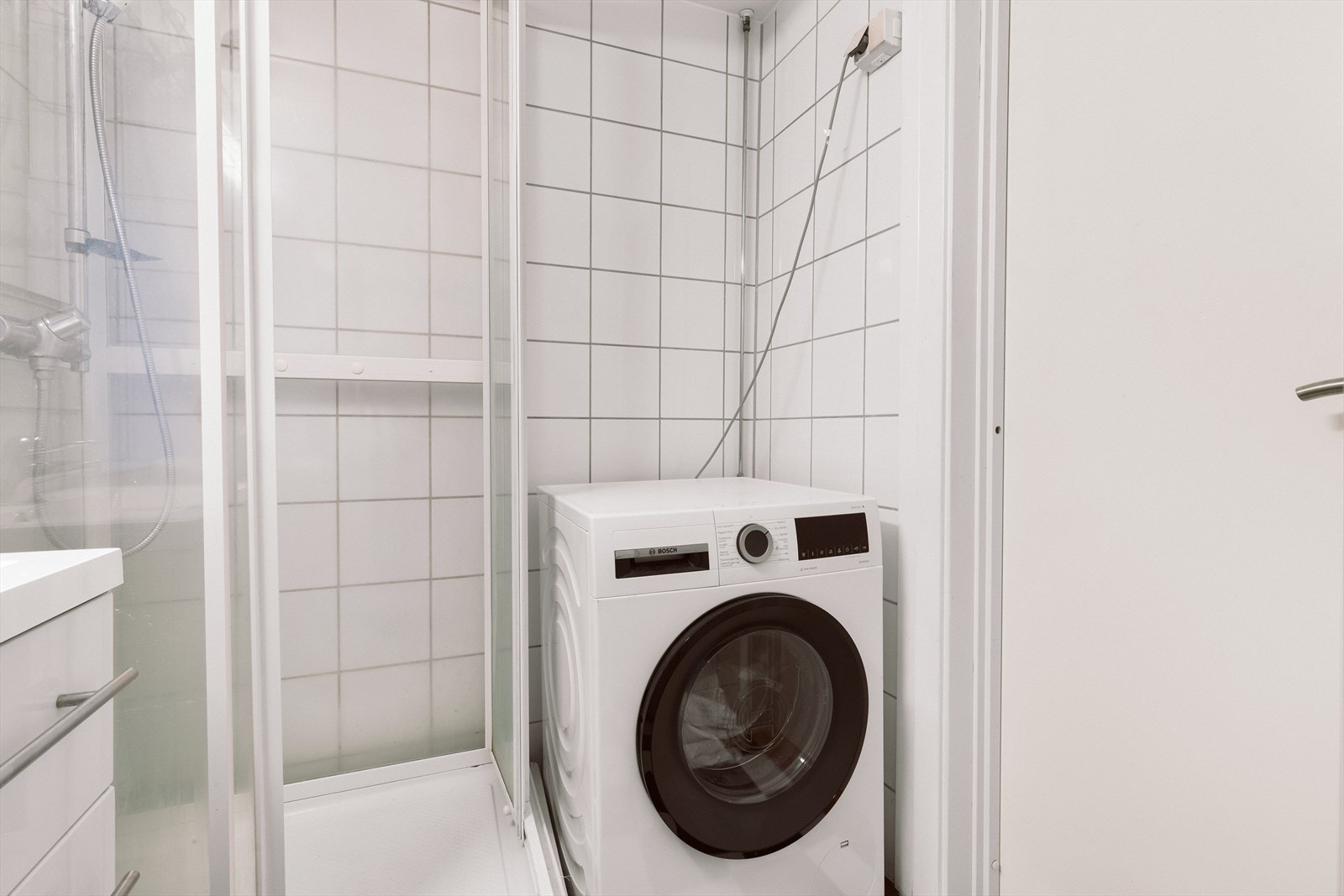 Det er et praktisk dusjkabinett og opplegg for vaskemaskin. Galleribilde