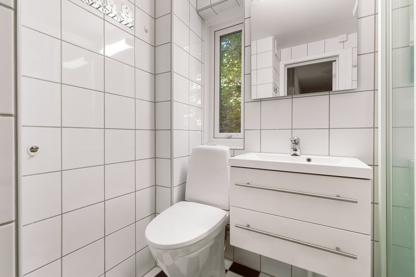 Innredningen består av servantskap, speil med belysning og et gulvmontert toalett. Galleribilde