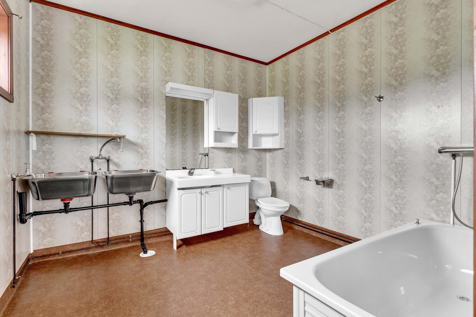 Baderommet i første etasje er et kombinert bad/vaskerom med vinylbelegg på gulvet og lyse våtromsplater på veggene. Galleribilde