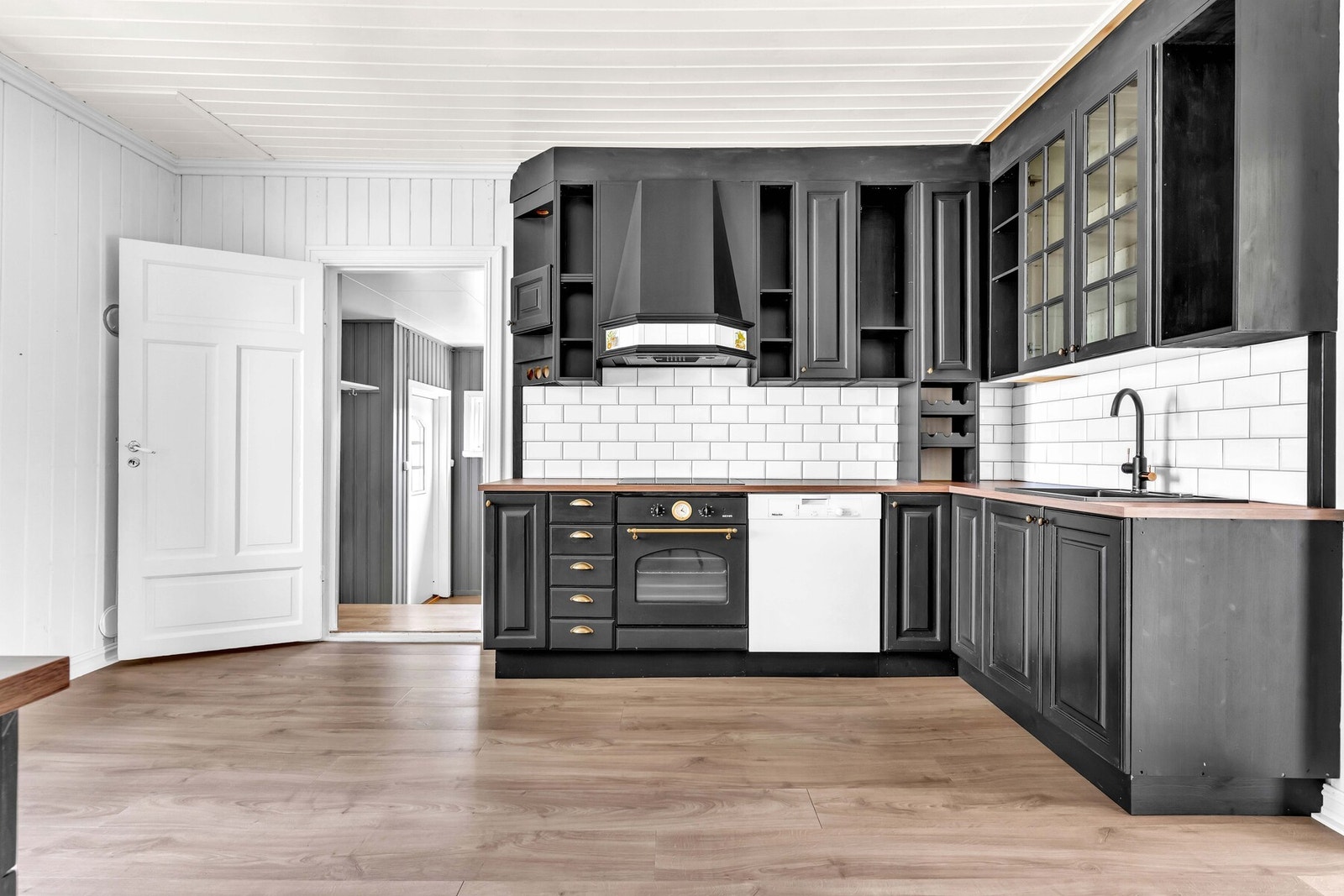 En heltre innredning er oppført i en funksjonell L-form med god arbeidsflyt og skapplass, supplert av et matchende benkeskap med skuffer for ekstra oppbevaring. Galleribilde