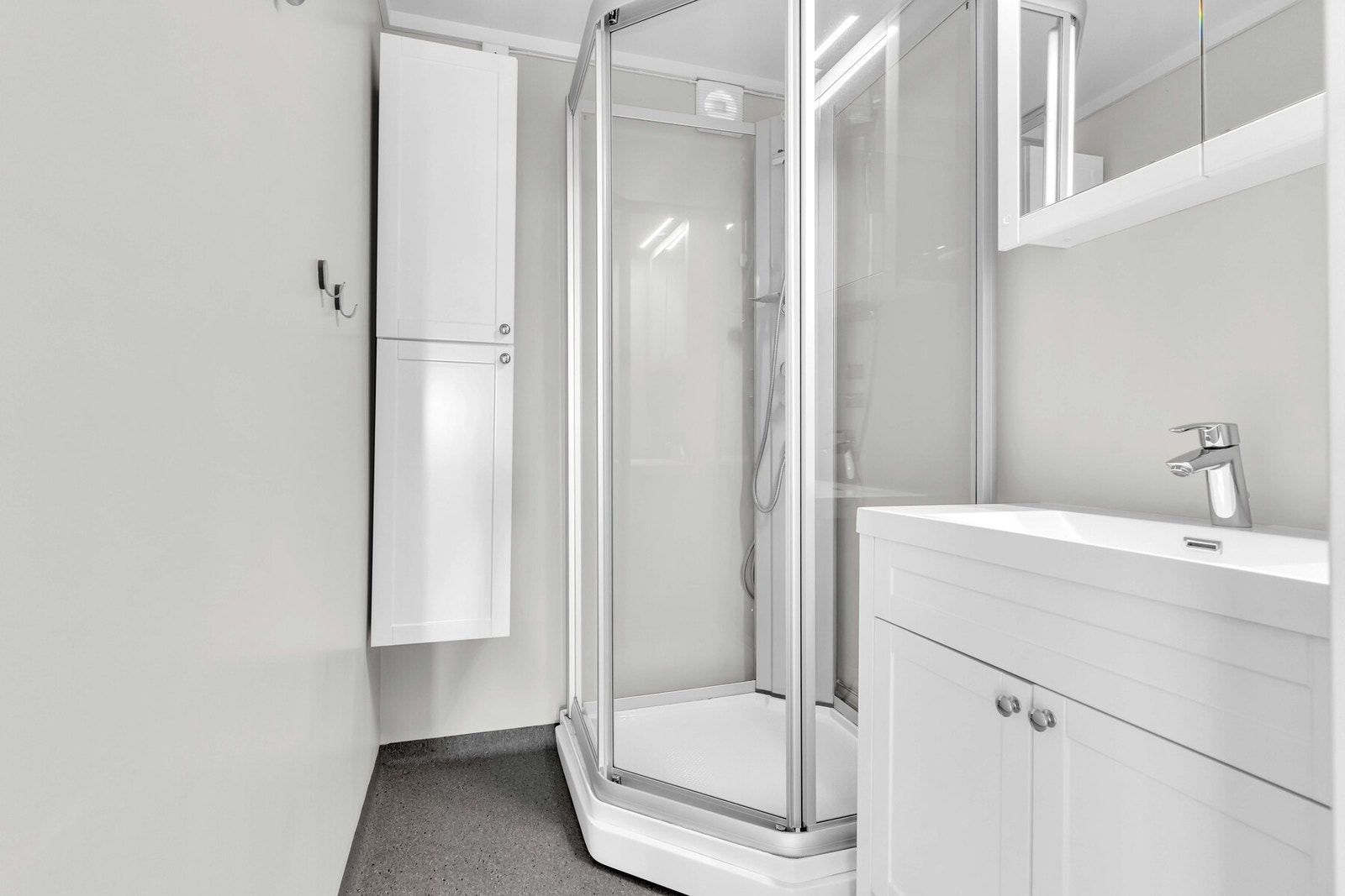 Badet i loftsetasjen har innredning med heldekkende servant over servantmøblement, høyskap og speilskap med belysning. Videre har badet dusjkabinett. Galleribilde